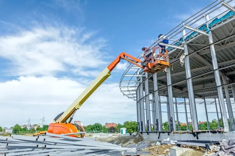 Crane lifting steel beams during construction of a large building