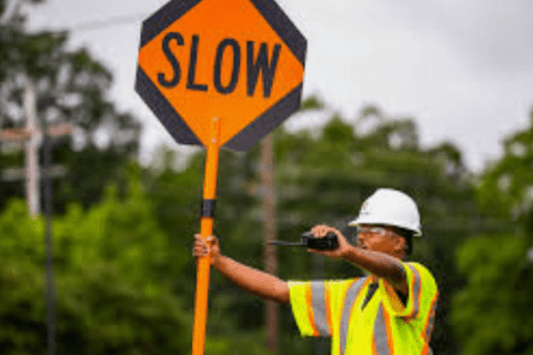 Road worker holding a slow sign while directing traffic at a work zone