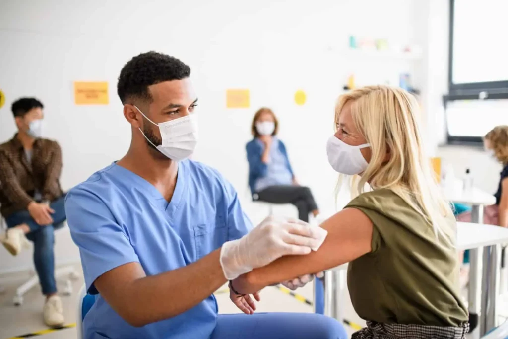 Healthcare worker administering a vaccine to a seated adult in a clinic