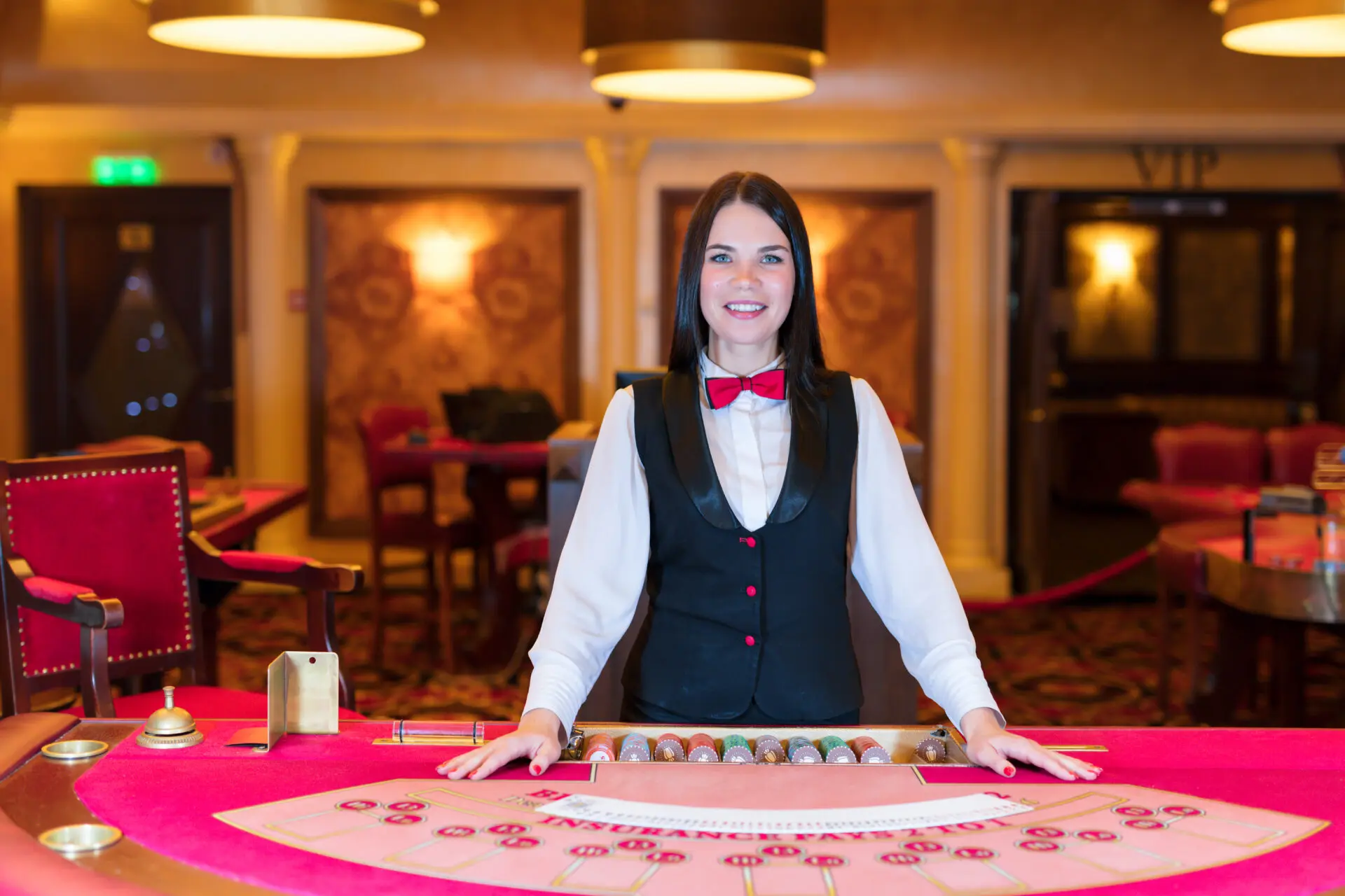 Casino dealer standing behind a gaming table with chips laid out