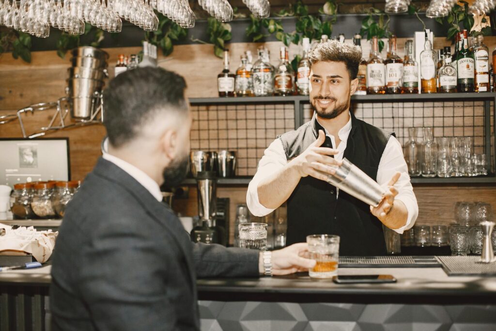 Bartender shaking a cocktail while talking to a customer at the bar