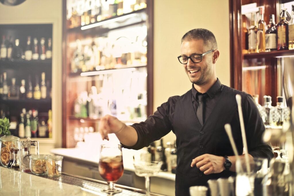 Bartender garnishing a cocktail behind a bar counter