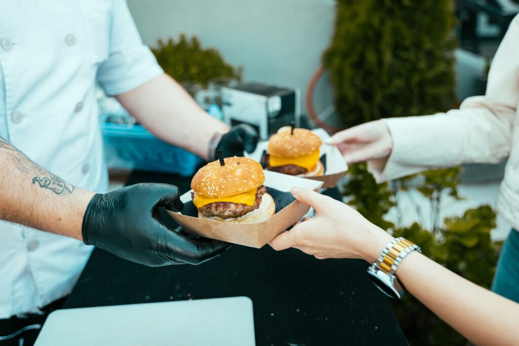 Burgers being handed to a customer at a street food stall