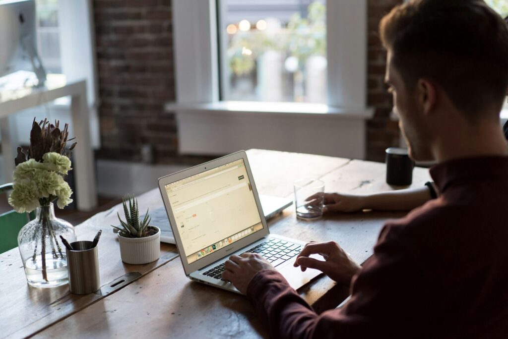 Man working on a laptop at a wooden table