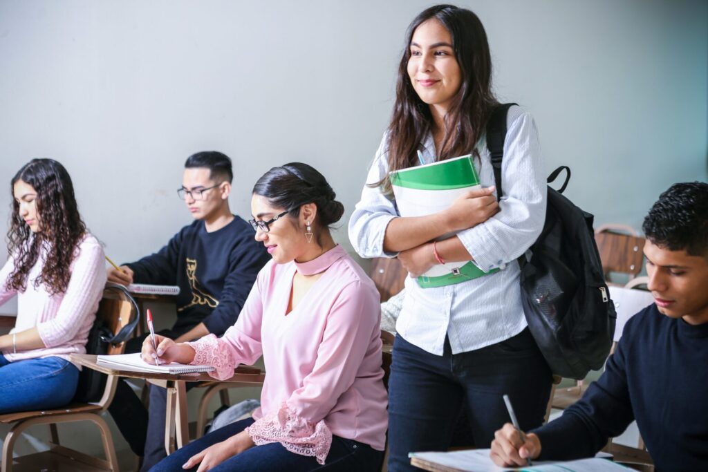 Female student in a classroom standing up and listening to the teacher