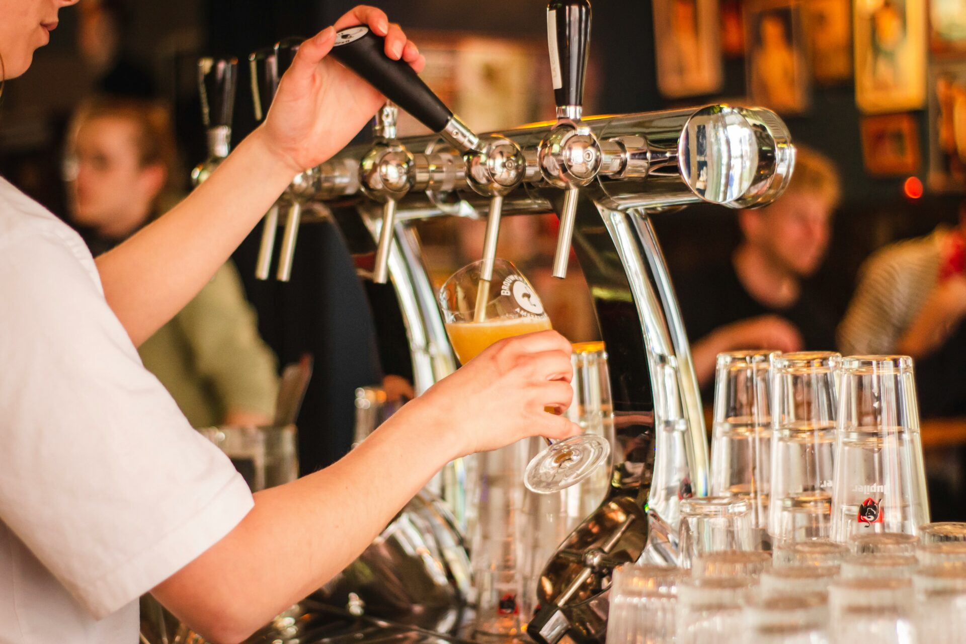 Bartender pouring beer from taps in a busy pub