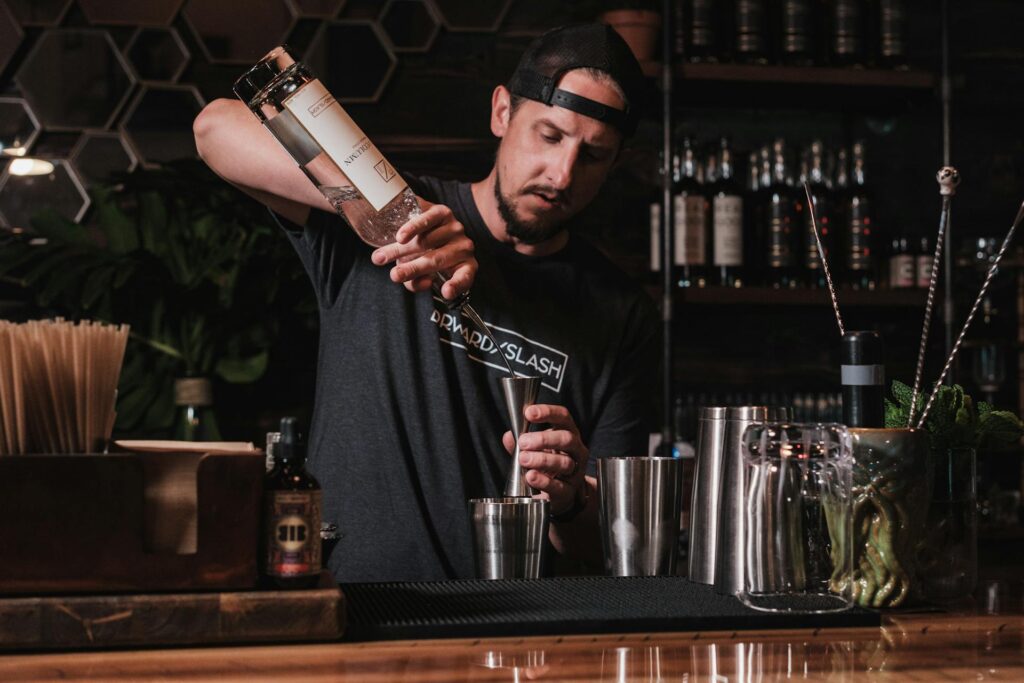 Bartender pouring spirits into a jigger behind a bar