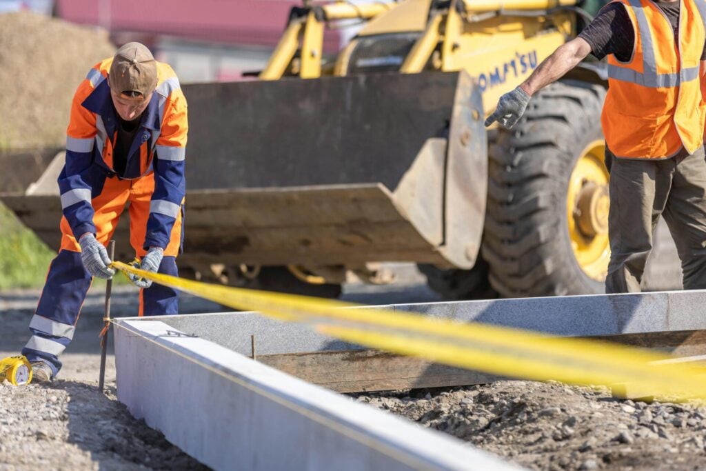 Construction worker measuring a concrete foundation at a job site