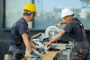 Two construction workers operating a saw on site